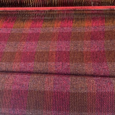 Loom showing detail of Bilberry and maroon weft across warp of rusty orange, raspberry and dull tan.